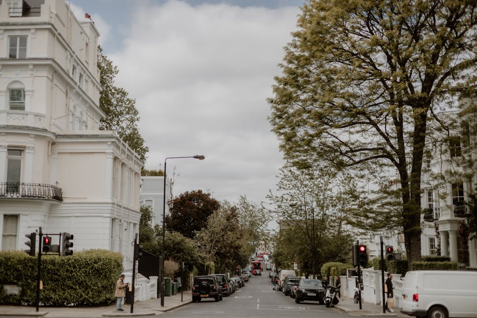 A street scene on Pentonville Road N1 featuring a variety of white, Victorian-style residential buildings with decorative facades and balconies. Several cars are parked along the curb, and a few pedes